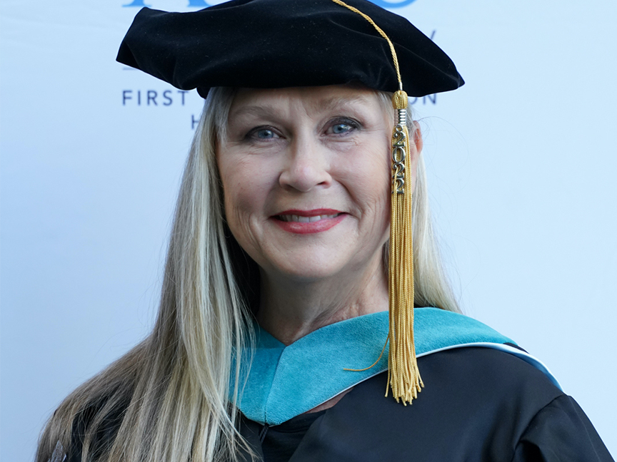 ATSU DPT graduate in cap and gown smiling at the camera