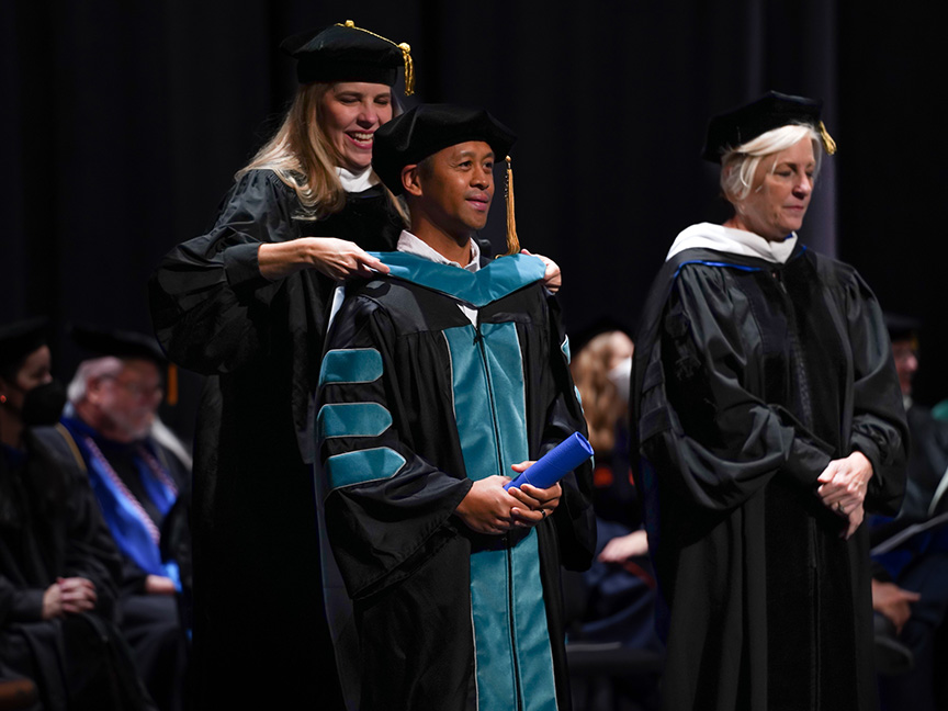 ATSU DPT student receiving an academic hood on stage during graduation