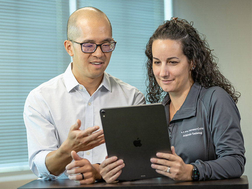 Two ATSU MSAT professors collaborating while reviewing information on an iPad