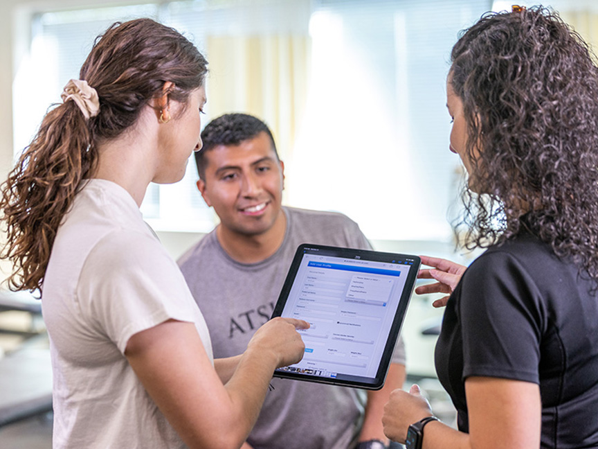 Three ATSU DAT students collaborating on a project while reviewing information on an iPad