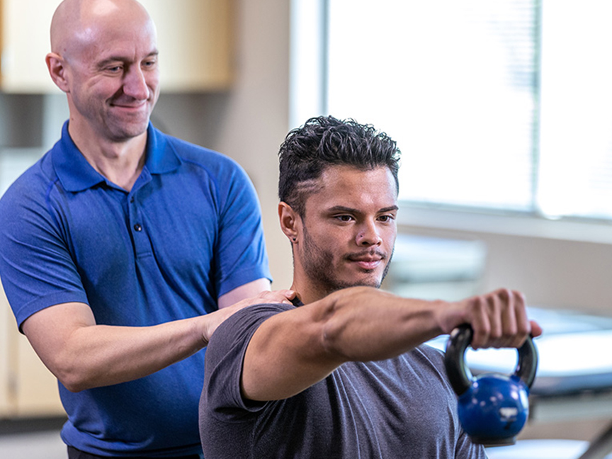 ATSU DAT trainer assisting a client with a kettlebell exercise for strength training