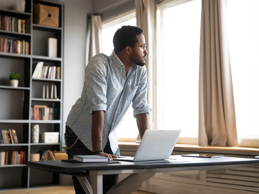 Master of Public Health student working at his home office desk on his computer, showcasing flexibility and online learning in the MPH program.