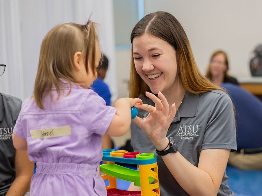 Entry-Level OTD student assisting a child with building a toy structure, showcasing therapeutic play and occupational therapy techniques for pediatric care.