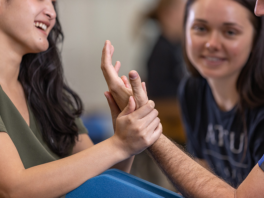 Entry-Level OTD students practicing hand exercises on each other, highlighting collaborative learning and hands-on occupational therapy training.