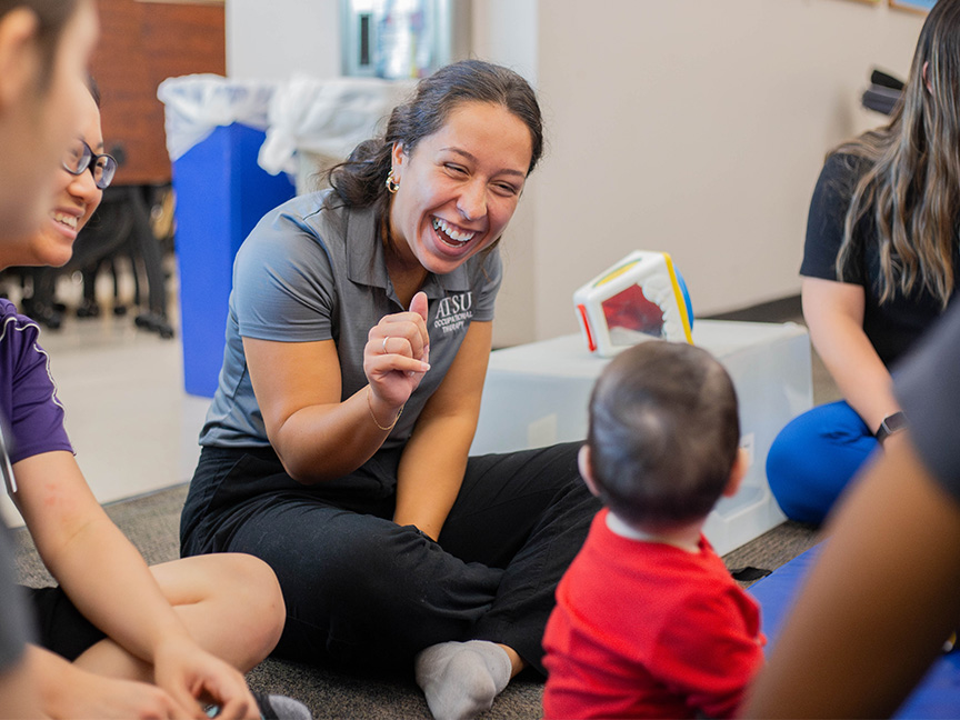 OTD students at ATSU engaging in hands-on therapy with a baby, practicing pediatric occupational therapy techniques.