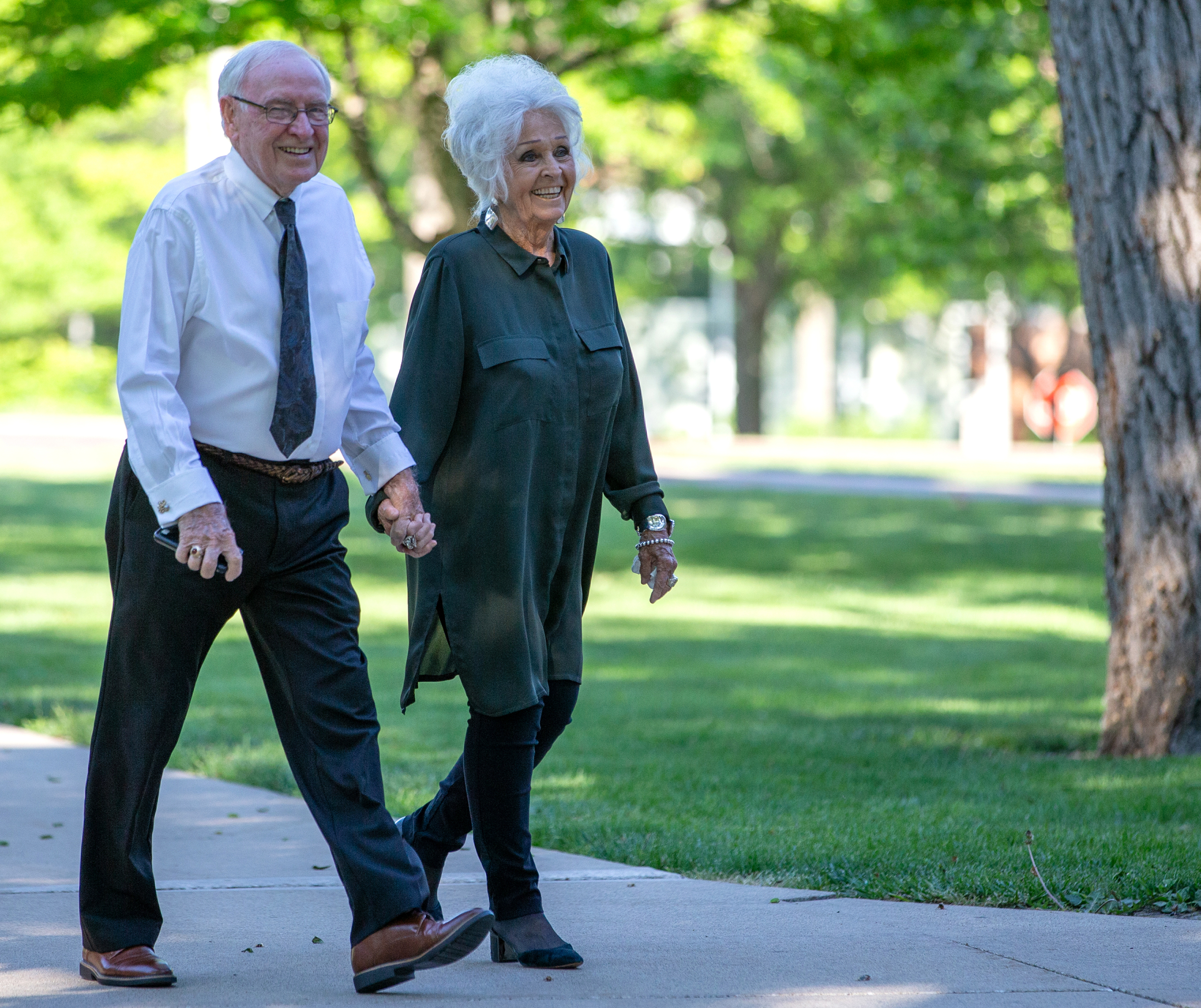 George, DO, ’76, and Elaine Pipes walking and holding hands on sidewalk