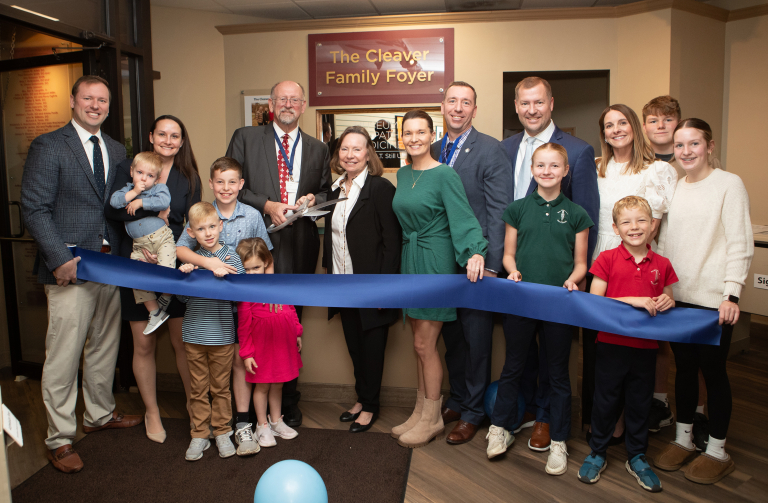 Cleaver family cutting a blue ribbon